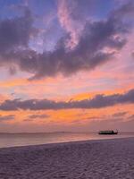 Purple Maldivian sunset, tourist boat in Indian Ocean, vertical photo