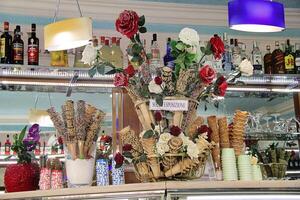 Rome, Italy - September 13 2022 Ice Cream Waffle Cups in Italian Restaurant with Beverages and Roses photo