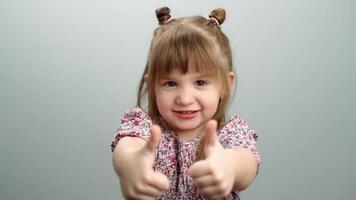 Background of children's emotions, a portrait of a girl showing a like finger. Child giving thumbs up happy and playful with a smile. High quality 4k footage video