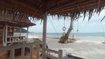 Thailand - 15e maart, 2024 - tijd vervallen strand retro cafe stoelen onder rietje dak met zee visie oosten- kust Thailand. time-lapse achtergrond video