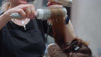 expert- hår vård. professionell frisör skapar underbar frisyr för kvinna använder sig av hårkam och hårtork, skön frisyr och frisyr Gjort förbi professionell, hår vård och hälsa. hög kvalitet 4k video