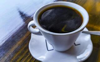 White cup of black Americano coffee on a wooden table. photo