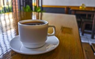 White cup of black Americano coffee on a wooden table. photo