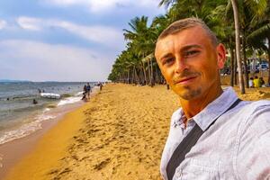 turista toma selfie playa olas arena personas palma Pattaya tailandia foto