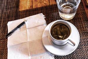 Cup of coffee with notepad and ballpoint pen on table Mexico. photo