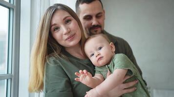 Lycklig familj på Hem. mor far innehav liten litet barn barn. mamma pappa bebis flicka koppla av spelar har roligt tillsammans. kvinna man kramas fattande bebis med kärlek vård. förälder av bröst matning bebis video