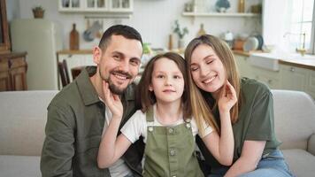 Happy family at home. Mother father children daughter relaxing on sofa indoor. Mom dad parents kid girl relax playing hugging having fun together. Family smiling laughing enjoying tender moment video