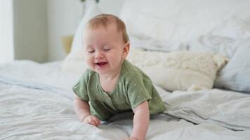 glücklich Baby. süß wenig Neugeborene Mädchen mit lächelnd Gesicht kriechen auf Bett im Schlafzimmer. Säugling Baby ruhen spielen Lügen Nieder auf Decke beim heim. Mutterschaft glücklich Kind Kinderbetreuung Konzept video