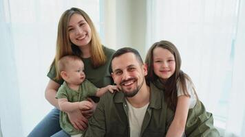 Happy family at home. Mother father two children daughters relaxing indoor. Mom dad parents baby girls kids relax playing having fun together. Family smiling laughing enjoying tender love moment video