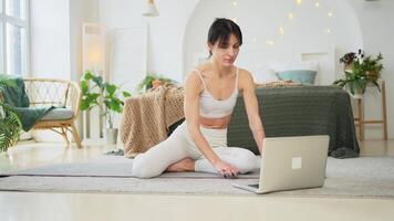 yoga aptitud rutina de ejercicio formación en línea. mujer practicando yoga con en línea lecciones en ordenador portátil a hogar. mujer haciendo Deportes ejercicio en yoga estera. niña tener formación rutina de ejercicio para peso pérdida. deporte aptitud video