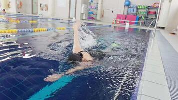 Professional female swimmer. Woman athlete swimmer training at swimming pool. Woman swimmer performing front crawl freestyle technique. Endurance sport professional swimming video