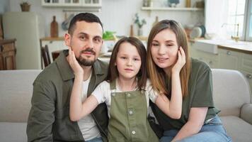 gelukkig familie Bij huis. moeder vader kinderen dochter ontspannende Aan sofa binnen. mam vader ouders kind meisje kom tot rust spelen knuffelen hebben pret samen. familie glimlachen lachend genieten van inschrijving moment video