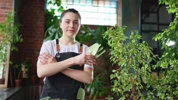 Laufen von besitzen Geschäft. jung Frau Florist tragen Schürze im botanisch Geschäft mit Grün Pflanzen. glücklich klein Geschäft Inhaber Arbeiten beim Blume Geschäft Stehen umgeben durch Pflanzen. klein Geschäft video