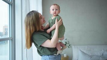 Lycklig familj på Hem. mor innehav liten litet barn barn dotter. mamma och bebis flicka koppla av spelar har roligt tillsammans på Hem. mor kramas kissing bebis med kärlek vård. mamma av bröst matning bebis video