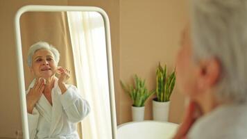 l'amour toi-même. magnifique vieux femme profiter miroir réflexion. Sénior plus âgée Dame dépenses Matin dans salle de bains à la recherche à miroir sur de soi heureux. femme Faire du quotidien Matin beauté routine. soi l'amour video