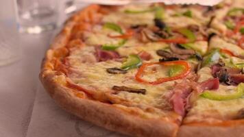 Close-up slow motion footage of large delicious pizza in greek tavern. Table setting. Customer service. Pizza with different toppings for a group of people. Mushrooms, piper, cheese, ham video