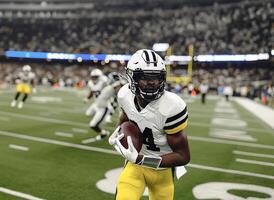 American football players in a white helmet and uniform hold the ball in their hands during a football match photo