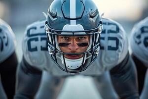 American football player in a gray helmet and white uniform stands waiting for the ball to be drawn photo