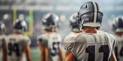 American football players in a gray helmet and white uniform stand with their backs during a football match. On the background of a grandstand with fans. Copy space photo