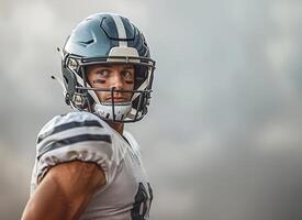 American football player in a gray helmet and white uniform with black stripes under his eyes, he stands sideways looking to the right. Copy space photo