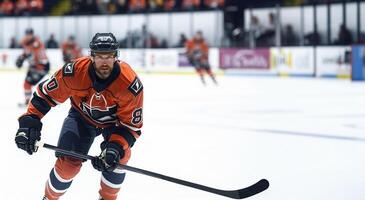 A hockey player in a black and orange uniform rides on the ice in the hockey arena with a raised stick. Copy space photo