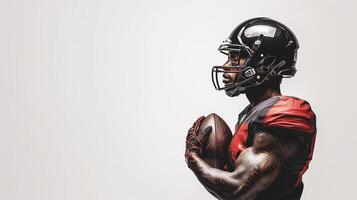 An American football player with a ball in his hands stands with his left side on a white background. Place for the text on the left photo