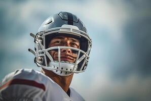 American football player in a gray helmet and white uniform smiles and looks pleased. Copy space photo