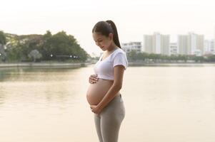 Portrait of Beautiful pregnant woman in the park, Healthy and active pregnancy lifestyle concept. photo