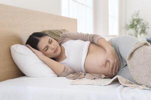 Pregnant woman feeling sick to her stomach, holding belly, having abdominal cramps, uncomfortable. photo