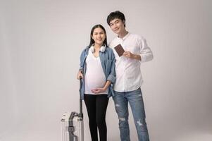 Portrait of Beautiful pregnant woman and husband traveling over white background studio, insurance and maternity concept photo