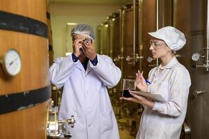 Professional winemaker controlling wine making process and quality at winery factory photo