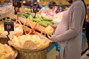 hermosa embarazada mujer compras sano comida a tienda de comestibles tienda foto