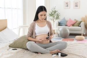 Pregnant woman checking blood sugar level by using Digital Glucose meter, health care, medicine, diabetes, glycemia concept photo