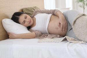 Pregnant woman feeling sick to her stomach, holding belly, having abdominal cramps, uncomfortable. photo