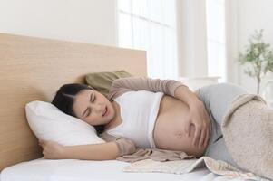 Pregnant woman feeling sick to her stomach, holding belly, having abdominal cramps, uncomfortable. photo