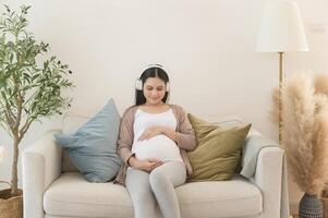 Happy pregnant woman with headphones listening to mozart music and lying on sofa, pregnancy concept photo