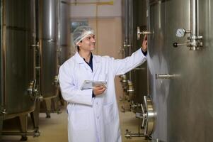 Professional winemaker controlling wine making process and quality at winery factory photo