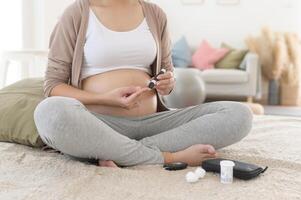 Pregnant woman checking blood sugar level by using Digital Glucose meter, health care, medicine, diabetes, glycemia concept photo