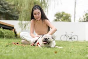 Happy asian woman playing with Cute Smart pug Puppy Dog In the Backyard photo