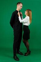 Young attractive business people in formal wear looking at each other. On a green background photo