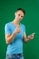 Young promoter man wear shirt white t-shirt point index finger camera on you indicate index finger aside on workspace area copy space mock up isolated on plain pastel green background studio photo