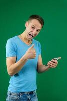 Young promoter man wear shirt white t-shirt point index finger camera on you indicate index finger aside on workspace area copy space mock up isolated on plain pastel green background studio photo