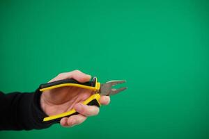 Hand hloding yellow pliers isolated advertising Green background chromakey hand pliers, And mechanic gloves. photo