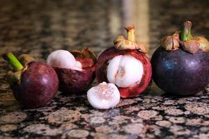 Mangosteen Ready to eatfruit of Thailand, selective focus asian thai mangosteen fruit stands on a marble table in a section a few pieces black background tropical fruit looks like a parsley photo