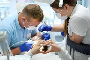 Woman showing heart with hands Professional tooth cleaning Dentist with assistant under microscope treats the patient's teeth. Modern progressive dentistry. photo