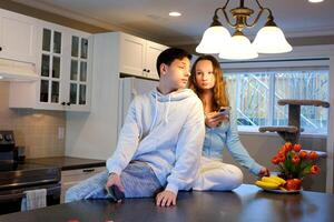 romántico sonriente Pareja joven chico y niña sentar en calentar cocina piso hablando participación lentes teniendo divertido juntos, contento simpático marido y esposa riendo disfrutando Bebiendo rojo vino a moderno hogar foto