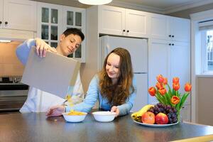 Loving daughter help mother and brother prepare breakfast before school. Healthy eating at home. Pleased teen girl pulls bottle of milk out of fridge for cornflakes. Happy family morning table time. photo