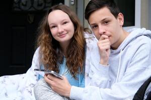 give a phone number to take a girl home from university school, a guy and a woman, a girl, phone in hands, order delivery, look at a new gadget app on the phone, look into each other's eyes, be shy photo