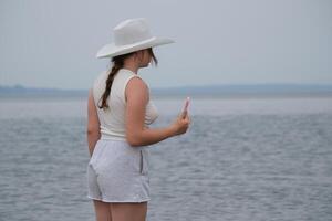 Girl using cellphone on a sea ocean shore. Young girl on the beach with your smartphone. photo