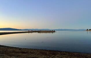 sunset on the Ocean Calmness calm sea on Vancouver Island resting in trailers on the shore bright colors of dark blue orange stripe on the horizon from the sun rich space for text travel advertising photo